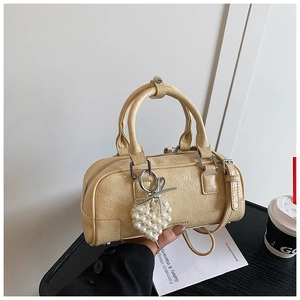 Detail of beige wrinkled patent leather mini boston bag with pearl heart charm decoration