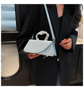 Détail du sac à main en cuir bleu clair avec une poignée métallique unique en forme de cœur