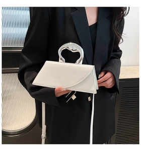 Détail macro du sac à main blanc géométrique avec poignée en métal argenté et cuir lisse