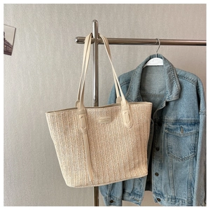 Detail of herringbone weave texture and beige leather straps on the woven tote bag