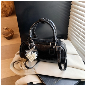 Detail of glossy black bowling bag with pearl heart charm and wrinkled texture