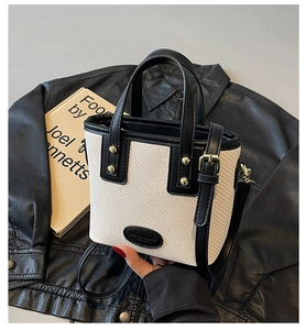 Détail de la texture tissée contrastée et des ferrures dorées sur le sac seau