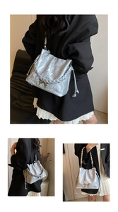 Close-up of silver pleated bucket bag with metallic drawstring and bow buckle detail