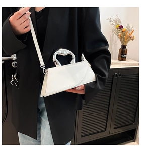 Vue détaillée d'un sac à main géométrique blanc avec poignée en métal argenté sur un modèle