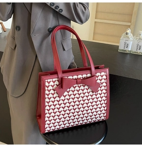 Detail of red bow accent and heart-patterned houndstooth texture on this tote bag