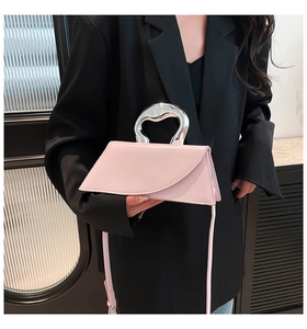 Détail d'un sac à main géométrique rose clair avec poignée argentée et texture cuir mat