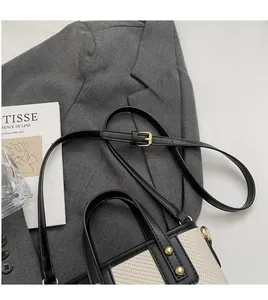 Détail du sac seau en tissu tissé beige avec bandoulière cuir noir et rivet doré