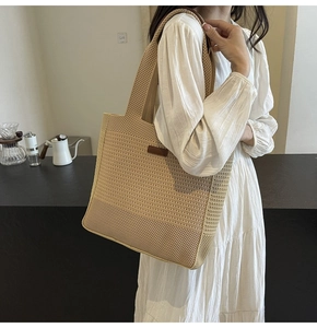 Detail of cream woven tote bag with leather patch on white dress shoulder