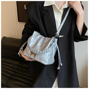 Detail of silver metallic drawstring bucket bag with butterfly buckle and woven handle