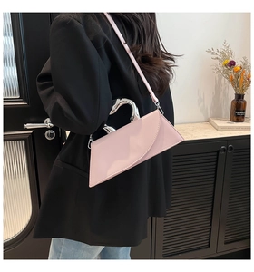 Détail d'un sac à main en cuir verni rose avec poignée argentée et bandoulière amovible