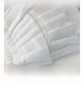 Close-up of white chiffon fabric with tiered ruffle layers and pleated edge details