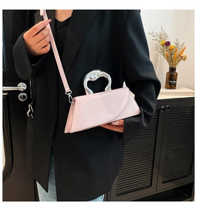 Gros plan d'un sac à main géométrique rose avec poignée en métal argenté et bandoulière