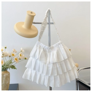 Detail of white tiered ruffle shoulder bag with soft chiffon texture and pleated strap
