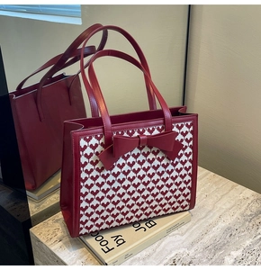 Detailed close-up of red tote bag featuring heart pattern fabric and a large bow decor