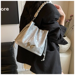 Detail view of silver bucket bag with woven strap and metallic butterfly clasp