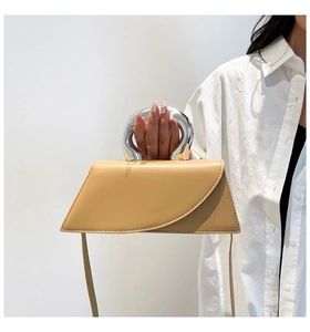Détail du sac à main beige élégant avec poignée ronde en argent et rabat incurvé