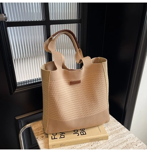 Detail view of the beige woven tote bag with premium brown leather handle and brand tag