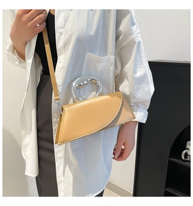 Détail du sac bandoulière abricot avec une poignée distinctive en métal argenté