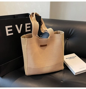 Beige knitted tote bag with wave texture placed on a leather sofa with a book
