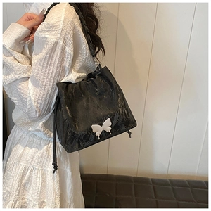 Close-up of black pleated texture shoulder bag with a contrast white butterfly detail