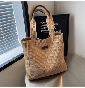 Detailed texture of beige woven tote bag with brown leather handle and rectangular patch