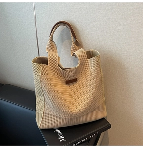 Close-up of beige crochet woven tote bag featuring leather handles and a brown brand label