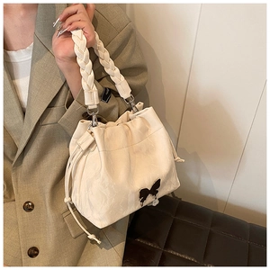 Detail of cream pleated bucket bag with black butterfly ornament and braided handle