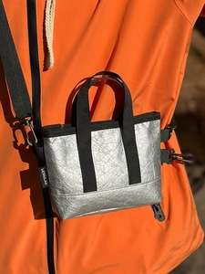 Silberne Umhängetasche mit metallischer Knitteroptik auf oranger Jacke