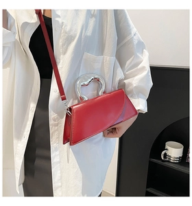Détail du sac à main en cuir verni rouge avec une poignée en métal argenté torsadé