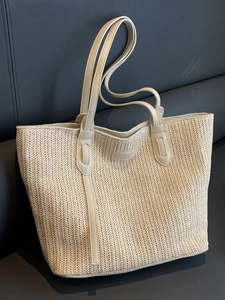 Large beige woven tote bag with slim shoulder straps and central logo for women's daily commute