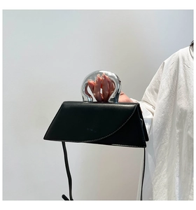 Vue détaillée d'un sac à main trapèze en cuir noir avec une poignée ronde en métal argent