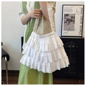 Detail view of the white tiered ruffles and pleated strap on this ballet style tote bag