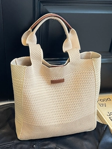 Chic beige woven tote bag with brown leather handles and a minimalist designer logo
