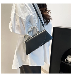 Détails d'un sac à main en cuir noir asymétrique avec poignée en métal argenté