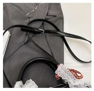 Detail of black leather handbag featuring lace trim and red plaid ribbon bow decoration