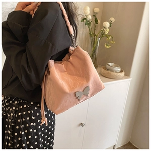 Pink drawstring bucket bag featuring silver butterfly detail and woven leather shoulder strap