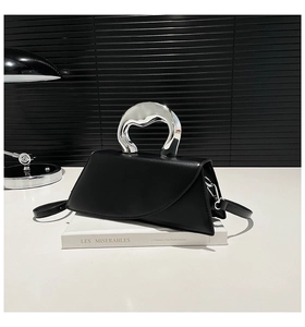Détail d'un sac carré noir chic avec poignée en métal argenté et finition lisse