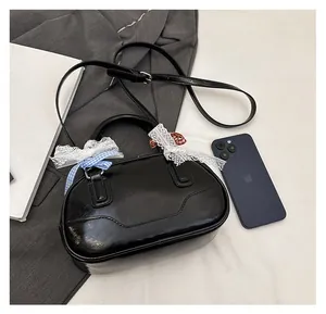 Detail of black Boston handbag with ribbon bows shown next to a smartphone for size reference