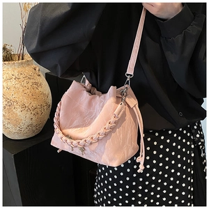 Detail of pink pleated bucket bag with braided handle and slim adjustable strap for women