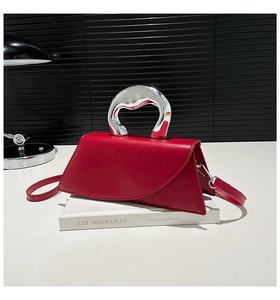 Détail artistique d'un sac rouge en cuir avec une poignée métallique argentée