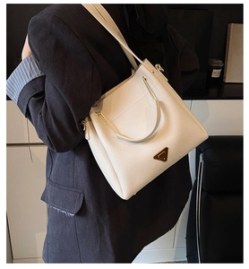 Detail of white lychee leather bucket bag with gold triangle plaque and hardware