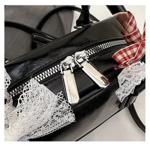 Detail of silver dual metal zippers on black glossy bowling bag with lace ribbon decor