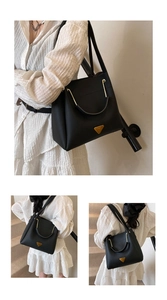 Detail of black lychee grain leather bucket bag with golden metal logo and elegant handle