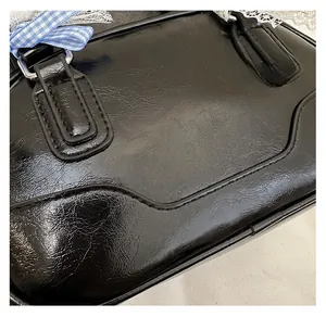 Macro view of black leather Boston bag featuring lace edges and blue checkered ribbon detail