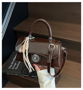 Détail du sac à main chocolat avec boucle argentée et breloques de sac de tennis