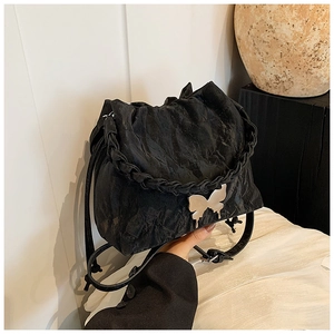 Detail of black bucket bag with silver butterfly buckle and braided handle detail