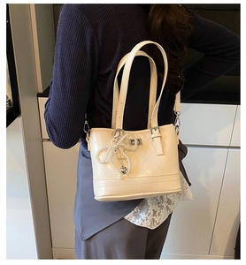 Detail of elegant cream white quilted handbag with pearl bow and silver heart charm