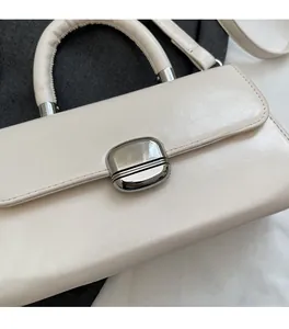 Close-up of creamy white faux leather small square bag with silver metal oval buckle