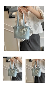 Detail of light blue quilted leather handbag with faux pearl bow and heart pendant charm