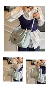 Detail of light blue lychee pattern leather bucket bag with metal triangle logo ornament